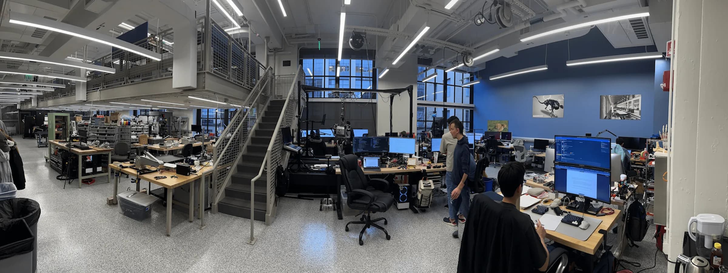 Robotics workshop with benches of hardware, test rigs and workstations under open ceilings.